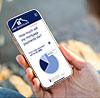 Phone held in hand. DHIMortgage.com Mortgage Calculator webpage open on phone.